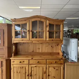 Houten buffettkast met glazen bovenkast en lademiddenkast, opgesteld in een kringloopwinkel