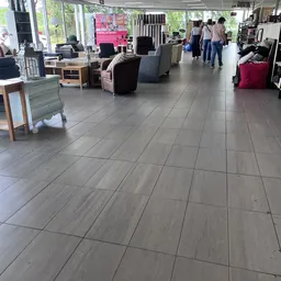 Winkelwloer met grijze tegels, displays met meubelstukken en bezoekers in de kringloopwinkel