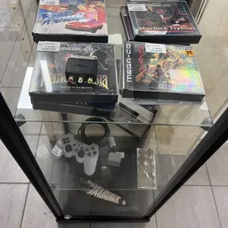 Vitrinecast met vintage gaming-artikelen: Atari-cartridges, controllers en game-dozen in een glazen kast