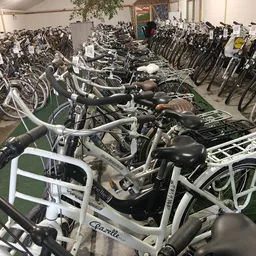 Rij met uitgstalde fietsen met witte frames en zwarte zadels in de winkel