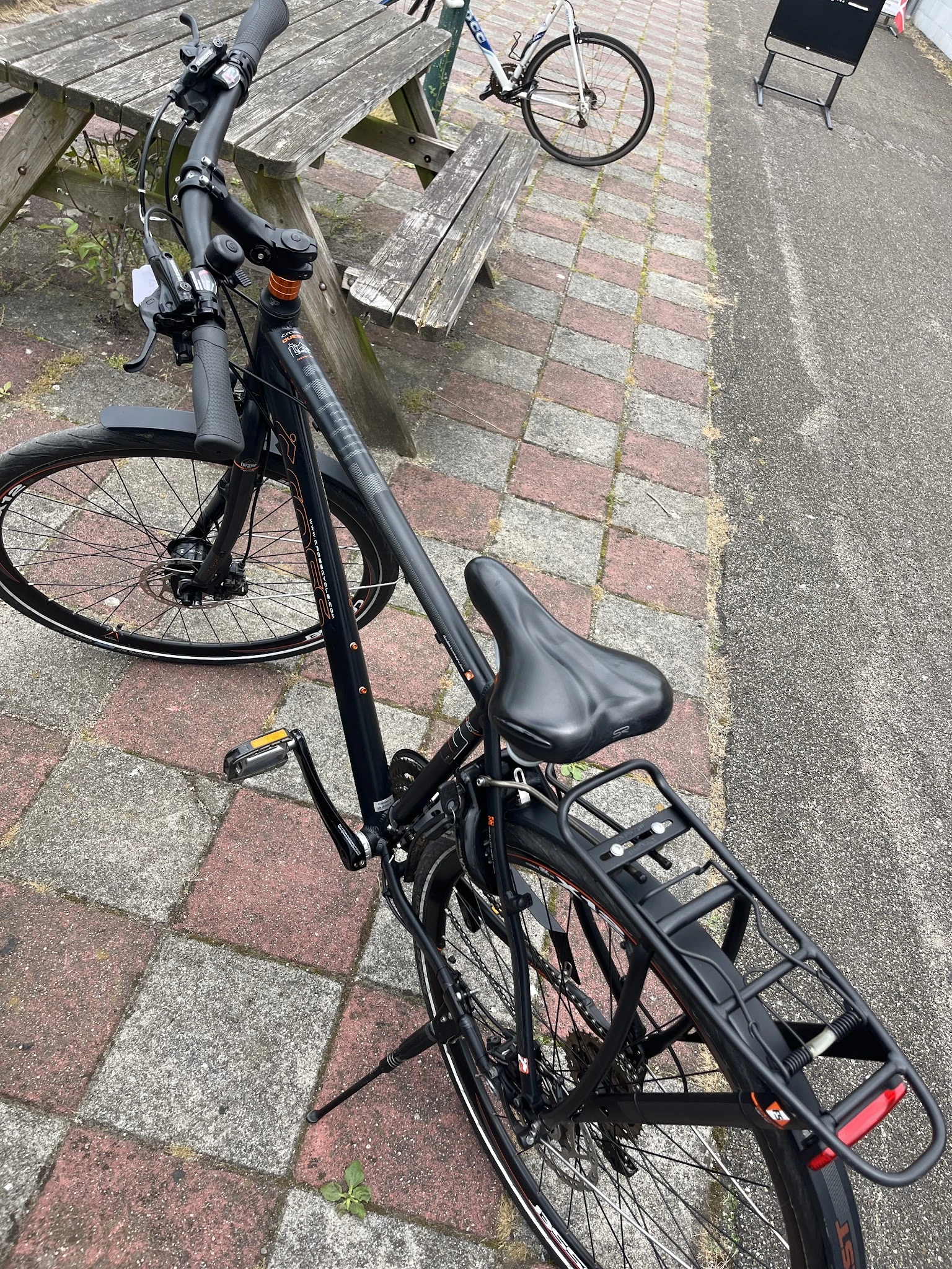 Zwarte fiets met zadel en bagagedrager op bestrating