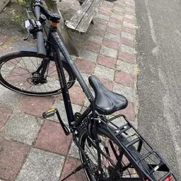 Zwarte fiets met zadel en bagagedrager op bestrating