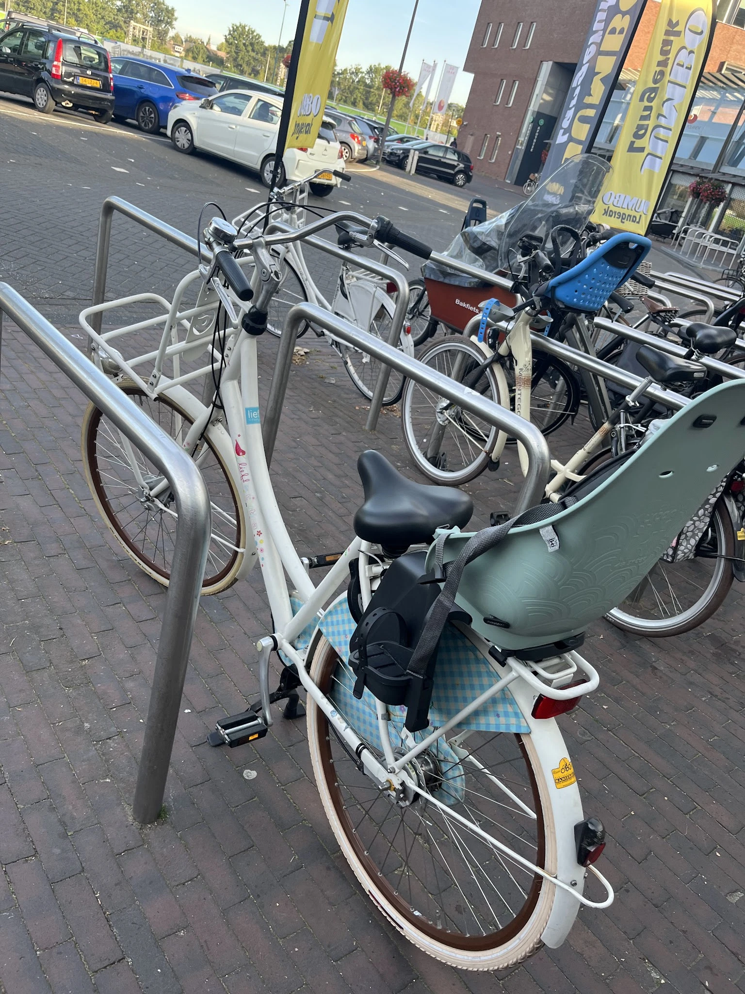Verschillende tweedehandsfietsenen fietsen in standaards op een parkeerplaats.
