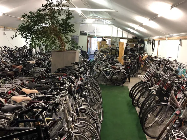 Fietsenstalling in een magazijn met honderden fietsen netjes op rijen uitgezet op groene vloer