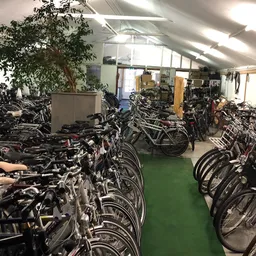 Fietsenstalling in een magazijn met honderden fietsen netjes op rijen uitgezet op groene vloer
