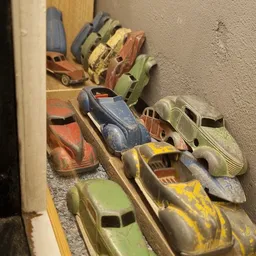 Verzameling vintage speelgoedauto's in verschillende kleuren uitgestald op een plank