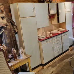 Winkelbinnenruimte met vintage keukenkasten, religieuze beelden en decoratieve objecten op tafels