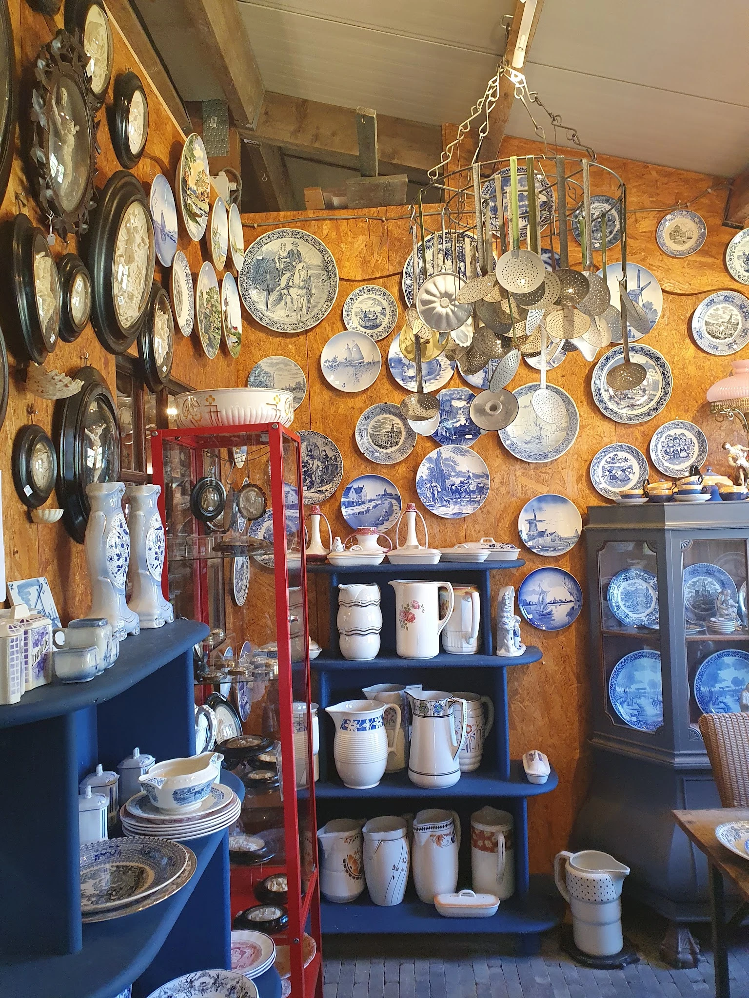 Verzameling antieke en vintage borden, servies en keramiek aan muur en schappen uitgestald