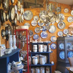 Verzameling antieke en vintage borden, servies en keramiek aan muur en schappen uitgestald