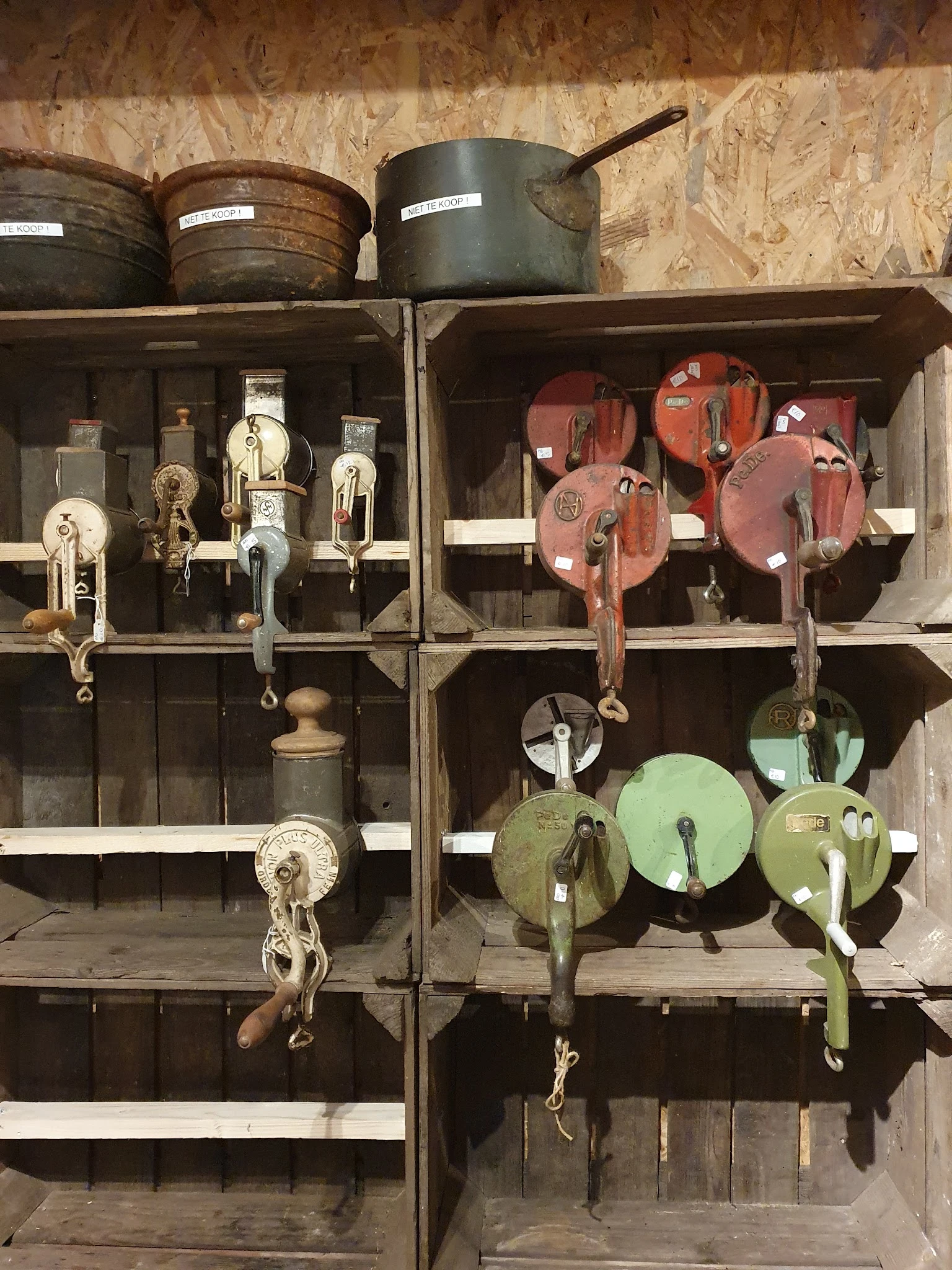 Vintage katrollen en riemschijven in verschillende kleuren uitgestald in houten kastjes