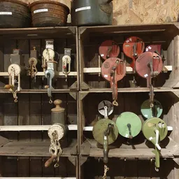 Vintage katrollen en riemschijven in verschillende kleuren uitgestald in houten kastjes