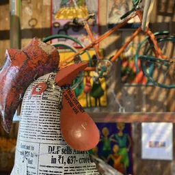 Close-up van decoratieve rode peren van papier-maché of karton met krantenprint, tegen achtergrond met fietsen en kunst