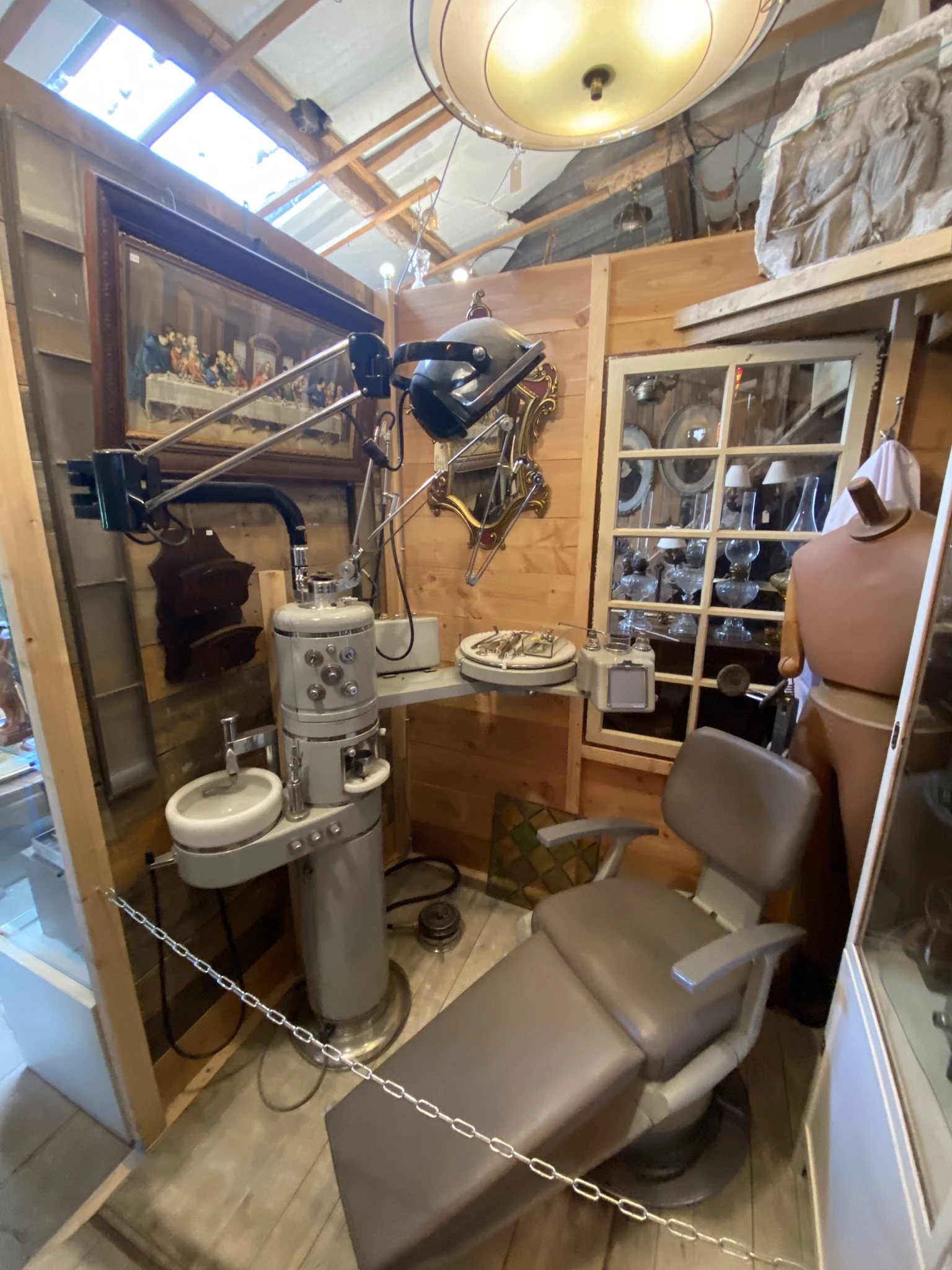 Vintage tandartsstoel en medische apparatuur in een glazen vitrine in de winkel