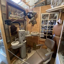 Vintage tandartsstoel en medische apparatuur in een glazen vitrine in de winkel