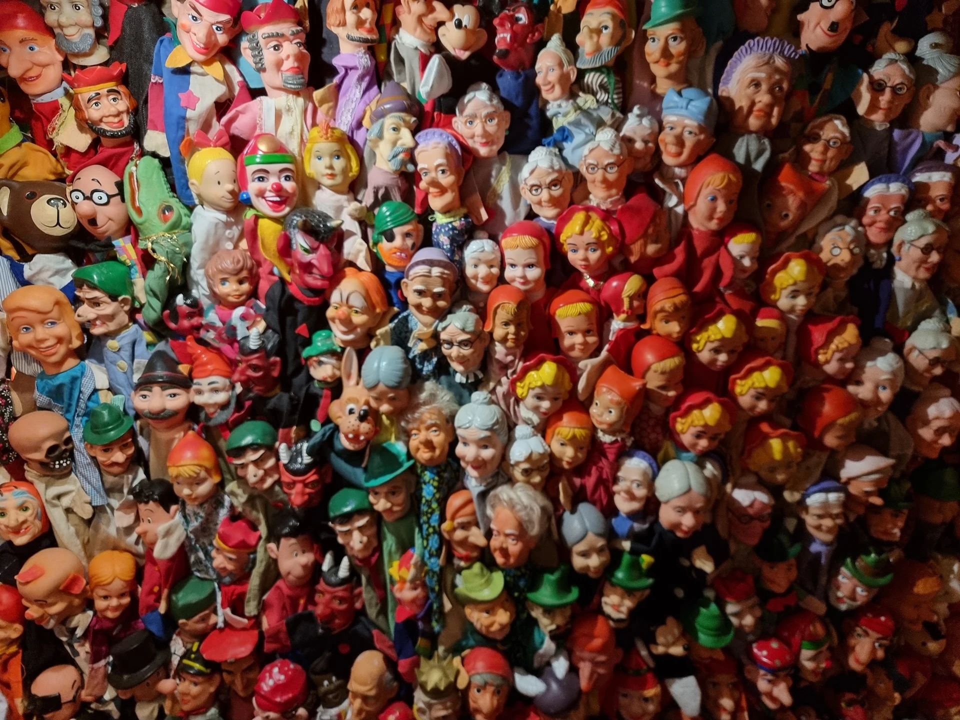 Grote verzameling kleurrijke vintage poppen en speelgoedhoofden op elkaar gestapeld