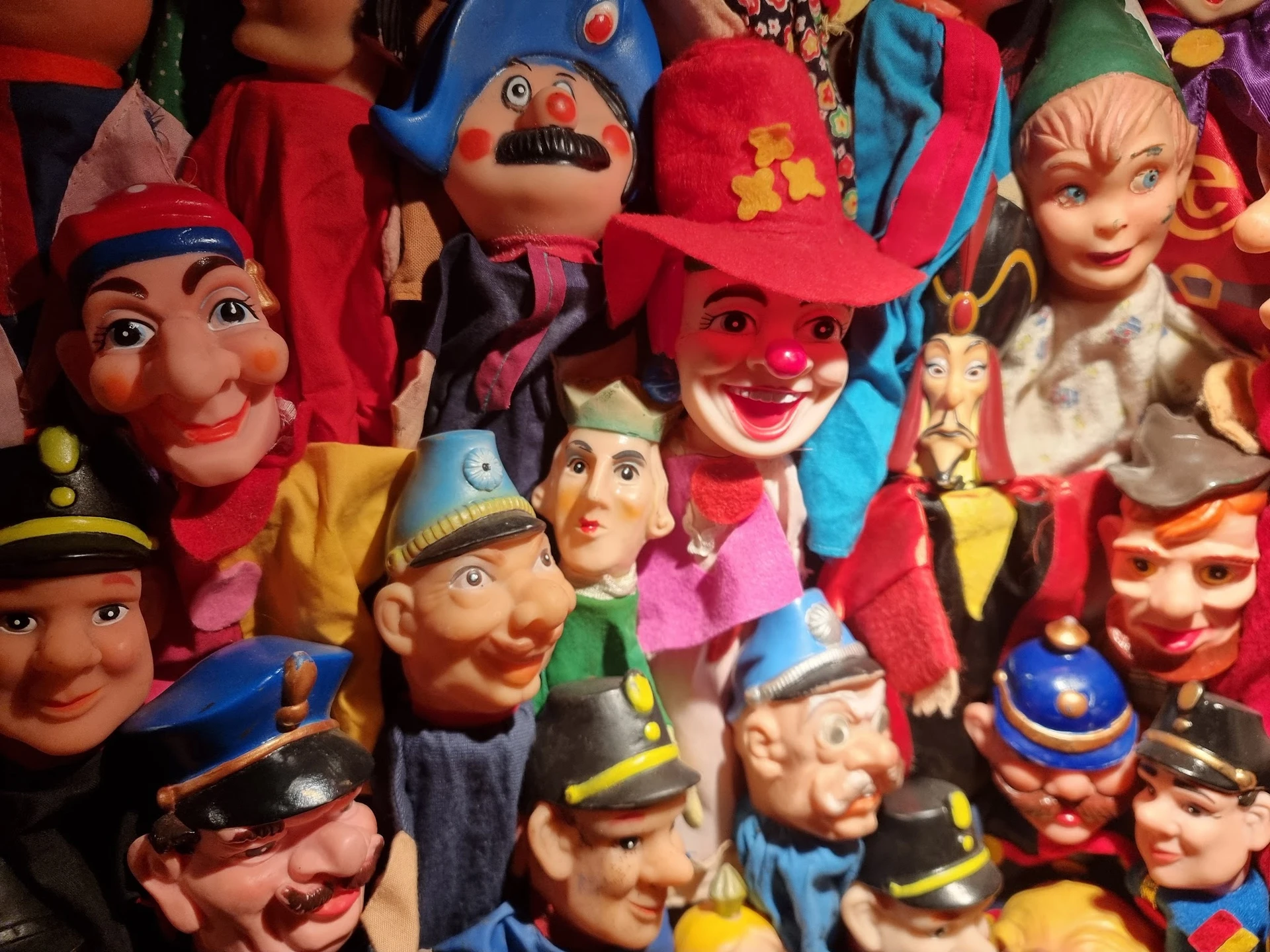 Verzameling vintage speelgoedpoppen en maskers, waaronder clowns en figuren in kleurrijke kostuums