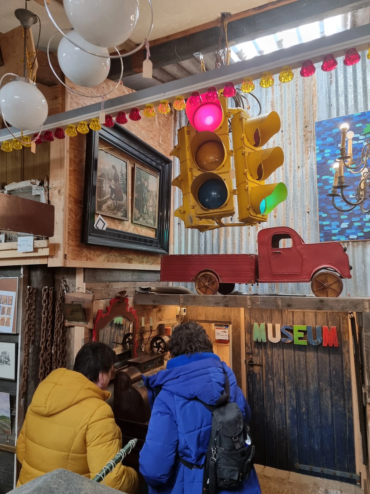Interieur van vintage winkel met verkeerslicht, rood speelgoedauto en museumbordje aan de wand