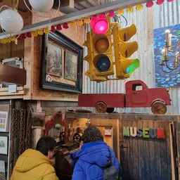 Interieur van vintage winkel met verkeerslicht, rood speelgoedauto en museumbordje aan de wand