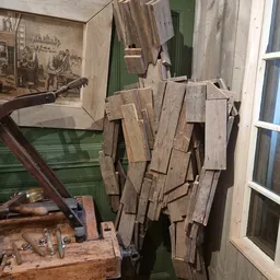 Verzameling oude houten planken en houtsnippers tegen muur, mogelijk bouwmaterialen of decorstukken
