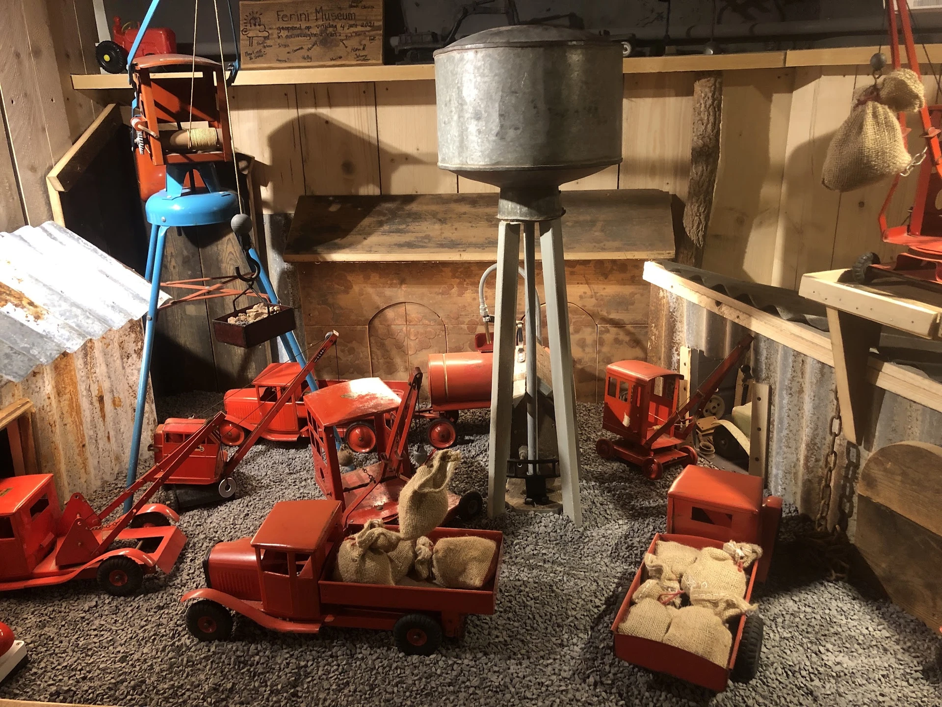 Tweedehands speelgoed en miniatuurauto's in rood en oranje uitgestald op grijze vloer in winkel