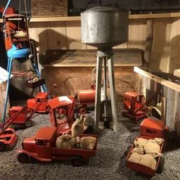 Tweedehands speelgoed en miniatuurauto's in rood en oranje uitgestald op grijze vloer in winkel