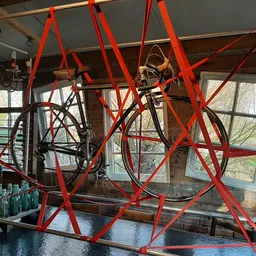 Interieur van winkel met rood stalen frame constructie en fiets opgehangen, grote ramen met uitzicht op straat