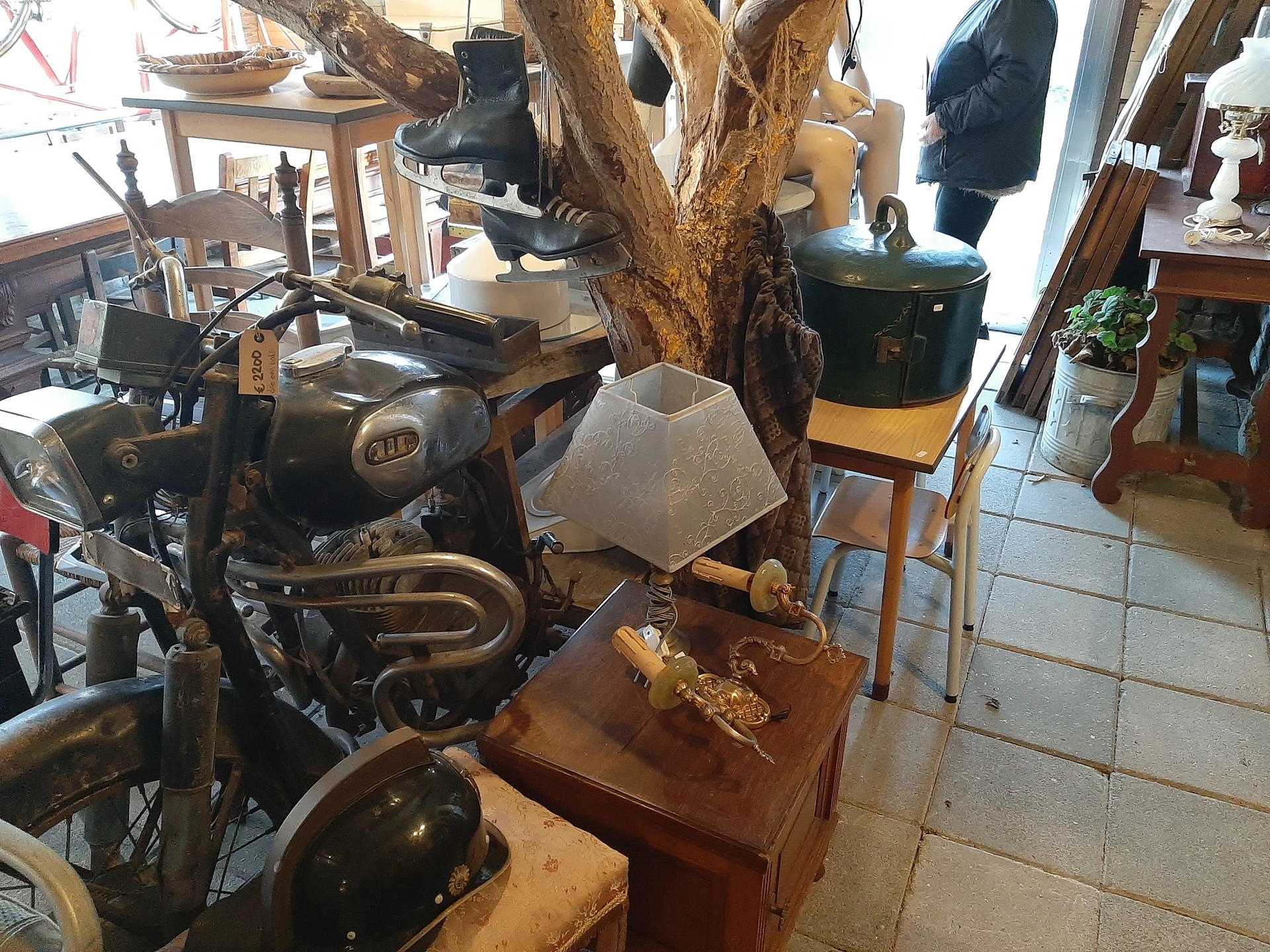 Winkelbinnenruimte met vintage meubels, kunstobjecten, een grote houten boomstronk-sculptuur en diverse tweedehands spullen