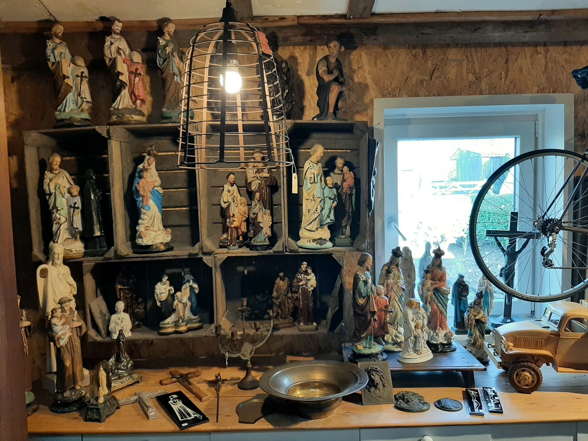 Vitrinekast met religieuze beelden, vintage lamp en andere antieke voorwerpen in tweedehandswinkel
