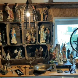 Vitrinekast met religieuze beelden, vintage lamp en andere antieke voorwerpen in tweedehandswinkel
