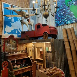 Winkelbinnenkant met vintage decorstukken: rood speelgoedauto, houten huisje, muurkaarten en ophangfiguren