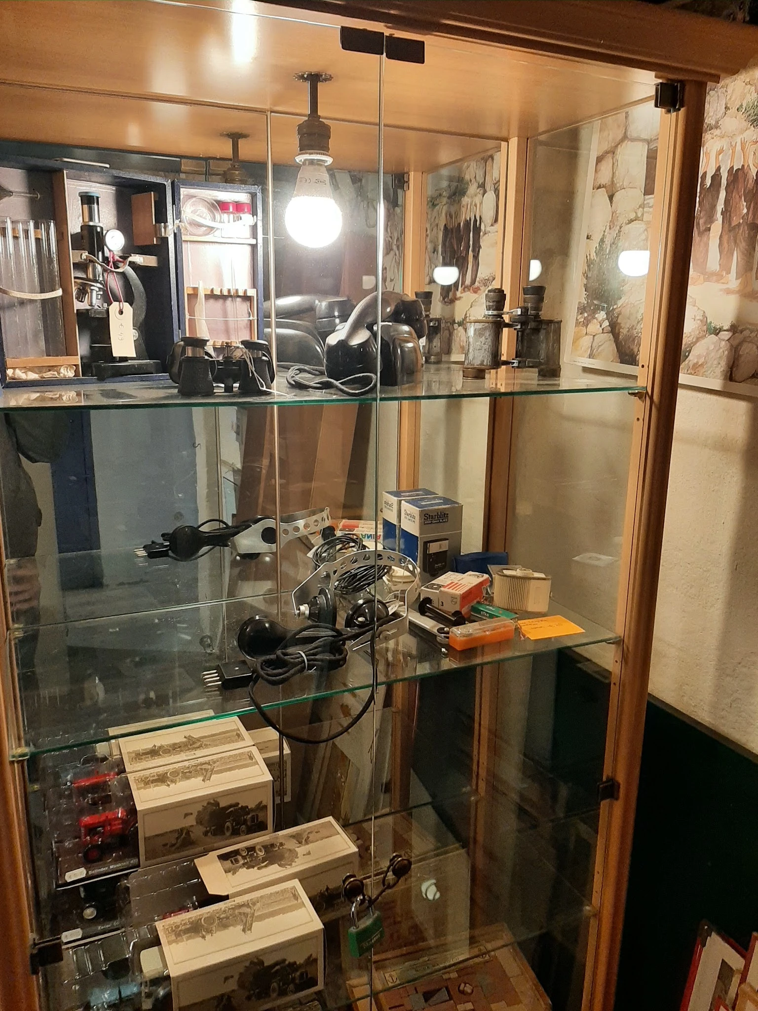 Glazen vitrinekast met vintage elektronica en apparaten, waaronder camera's en draadloze apparatuur