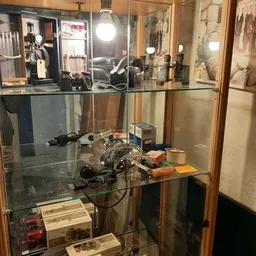 Glazen vitrinekast met vintage elektronica en apparaten, waaronder camera's en draadloze apparatuur