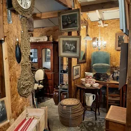 Vintage winkelinterieur met antieke meubels, schilderijen, servies en decoratieve voorwerpen tegen getextureerde wanden