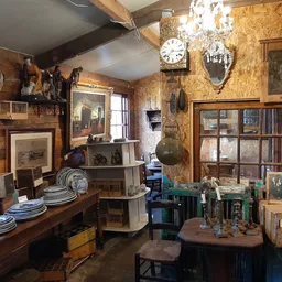 Vintage winkelinterieur vol antieke meubels, schilderijen, klokken, servies en decoratieve voorwerpen