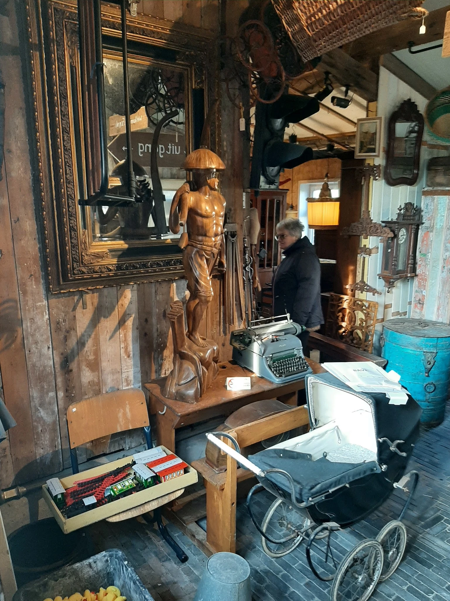 Interieur van vintage winkel met houten beelden, typewriter, spiegels en diverse tweedehandsartikelen