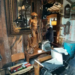 Interieur van vintage winkel met houten beelden, typewriter, spiegels en diverse tweedehandsartikelen