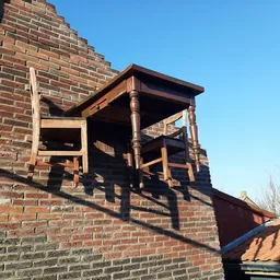 Bakstenen gevel met houten trap/constructie tegen de muur, tegen hemel