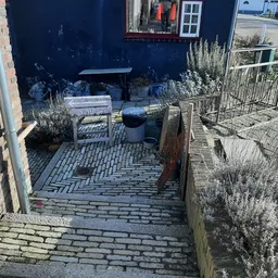 Binnenplaats of terras met herringbone-tegels, tuinmeubels en plantenbakken