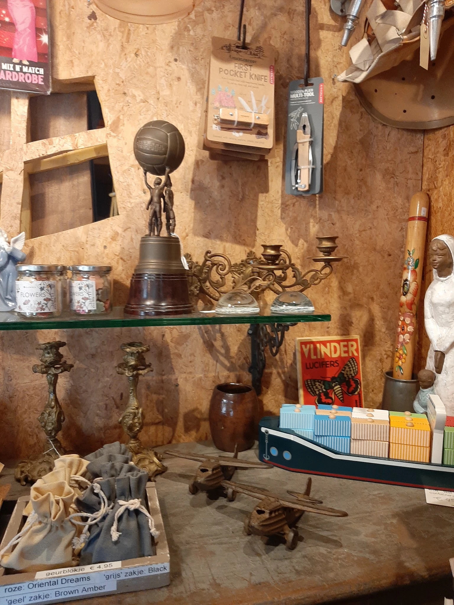 Vintage verzamelobjecten op groene glazen plank: bronzen beeld met basketbal, kandelaar, керамics, boeken en decoratieven.