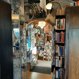 Smalle winkelruimte met boekenkasten, vintage spullen en posters aan de muren