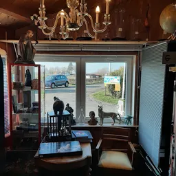 Winkelinterieur met uitzicht door grote ramen naar straat, standfiguren en diverse spullen in winkel zichtbaar