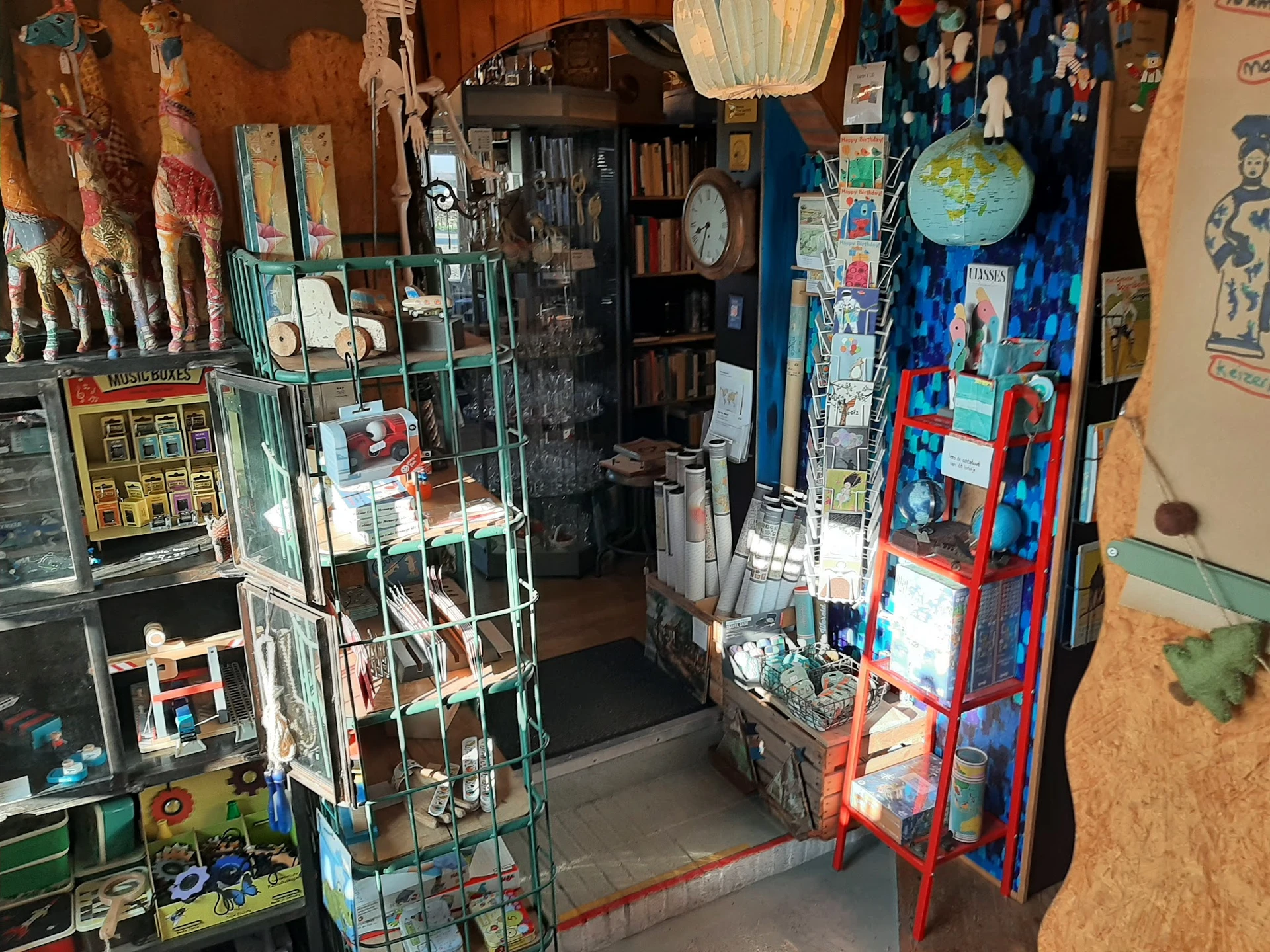Winkelinterieur met groene en rode stellingen vol boeken, vintage items en decoraties aan muren