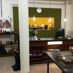 Winkelinterieur met kledingrekken, schoenenrekken, toonbank met gele achterwand en hangende verlichting