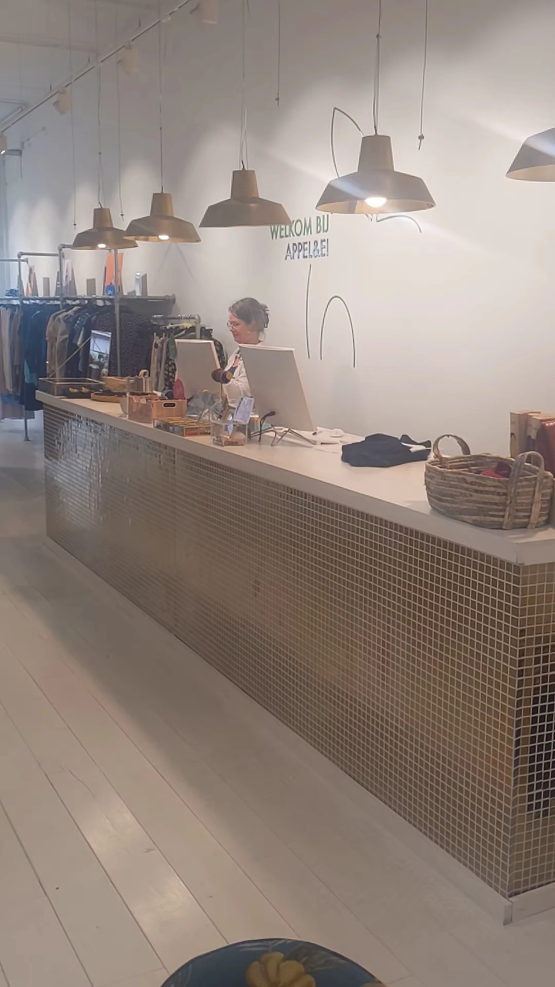 Medewerker achter de toonbank van een kringloopwinkel met kassa enDisplaySchepoddiensten