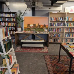 Boekenkast en leeshoek in een kringloopwinkel met boekenrekken, kunstwerk en zitgelegenheid