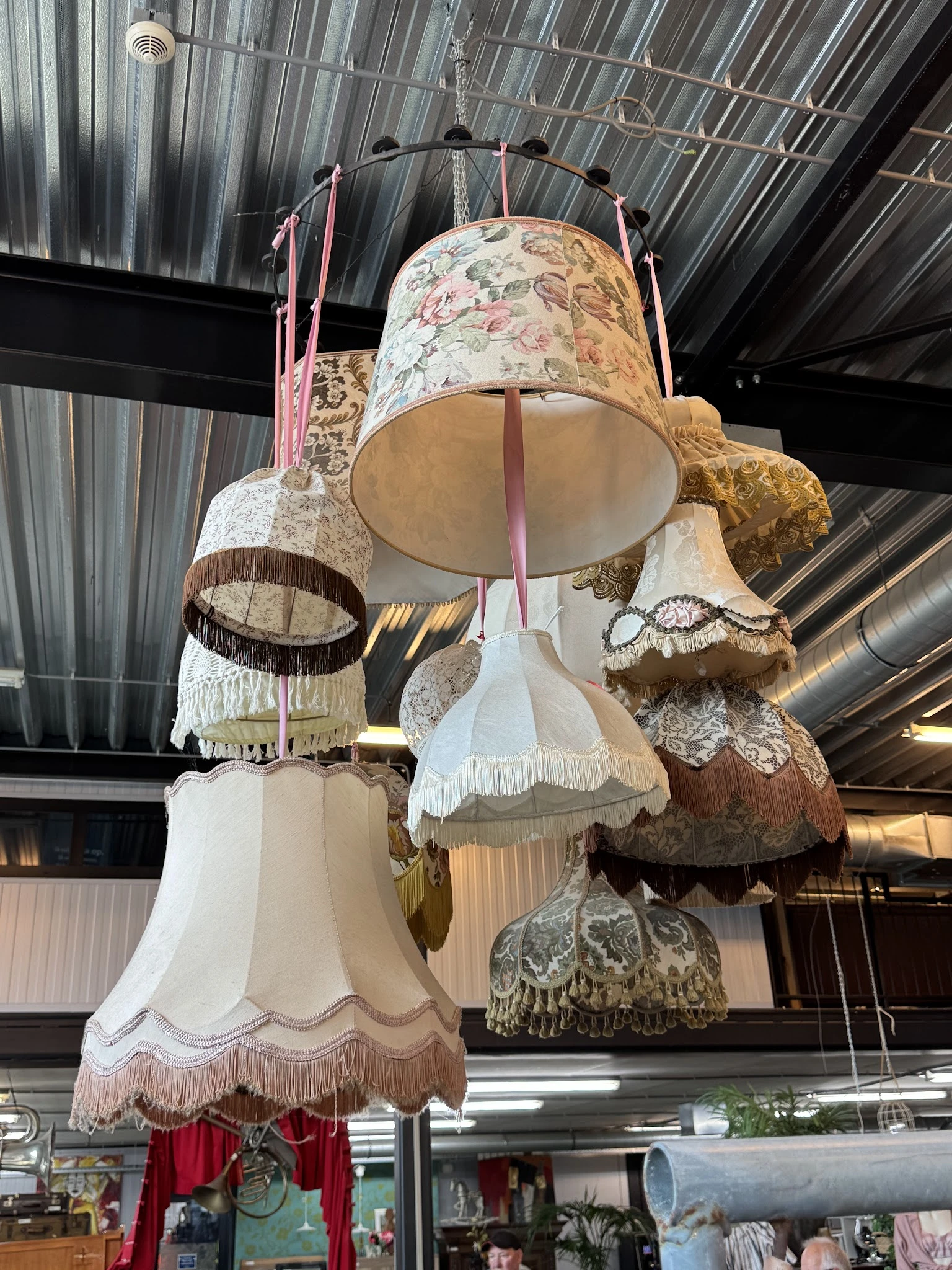 Verzameling van vintage hanglampenkappen met verschillende texturen en kleuren, opgehangen aan roze linten.