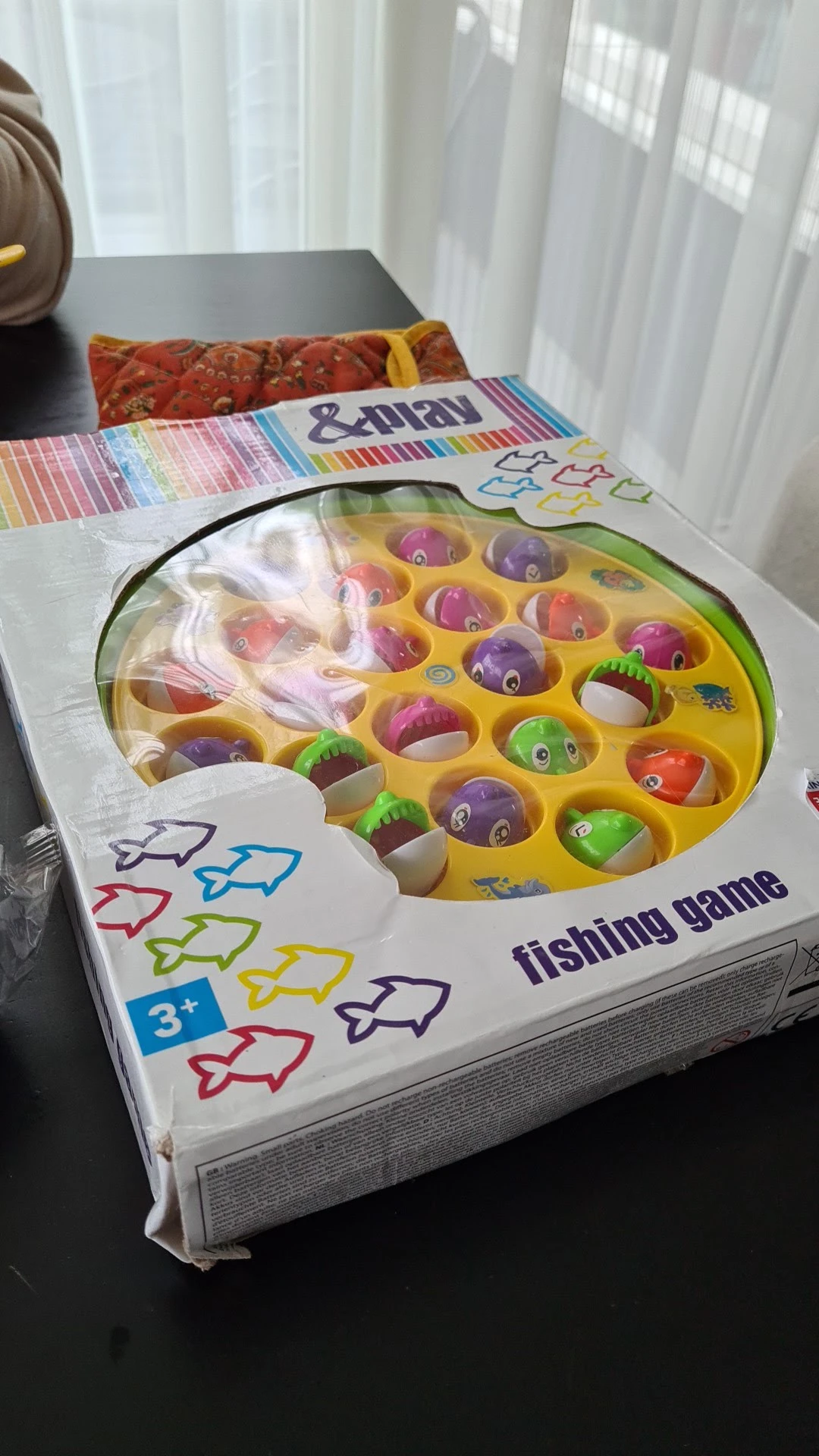 Geel speelgoedvissenspel met gekleurde ballen en hengels in verpakking