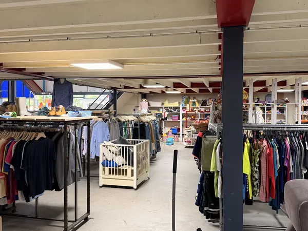 Winkelvloer met kledingrekken en een centrale kolom, overzicht van het tweedehands aanbod