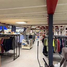 Winkelvloer met kledingrekken en een centrale kolom, overzicht van het tweedehands aanbod
