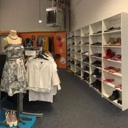 Winkelinterieur met kledingrekken, mannequins met kleding, witte stellingen met schoenen en accessoires
